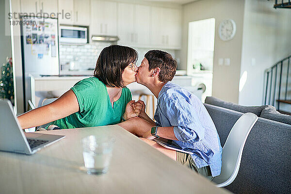 Liebevolles lesbisches Paar küsst sich von Angesicht zu Angesicht am Esstisch