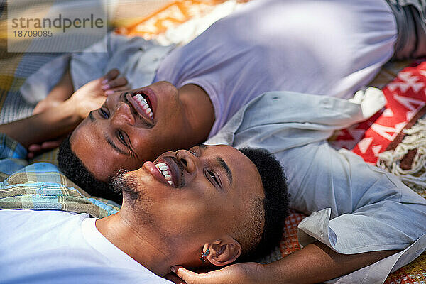 Nahaufnahme eines glücklichen  liebevollen jungen schwulen männlichen Paares  das auf einer Decke liegt