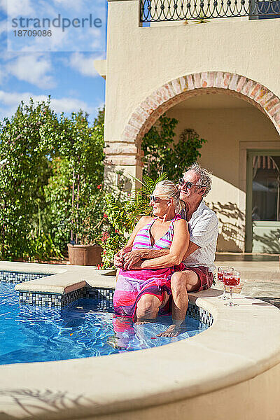 Sorgloses älteres Paar entspannt sich am Pool auf der Terrasse der Villa