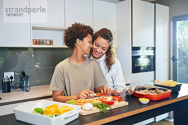 Glückliches  liebevolles lesbisches Paar  das in der Küche frisches Gemüse kocht