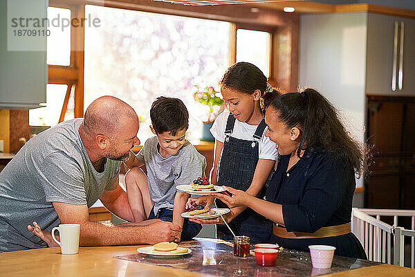 Glückliche Familie  die in der Morgenküche Pfannkuchen isst