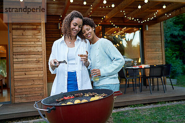Fröhliches  liebevolles lesbisches Paar beim Grillen im sommerlichen Hinterhof
