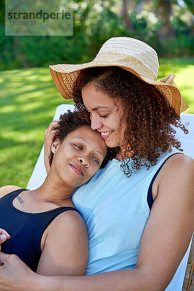 Glückliches  liebevolles lesbisches Paar  das im Sommer im Hinterhof kuschelt