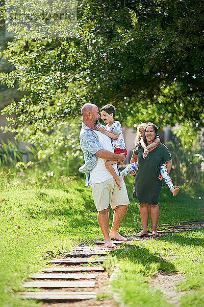 Glückliche Familie spaziert auf Fußweg im sonnigen Sommerpark