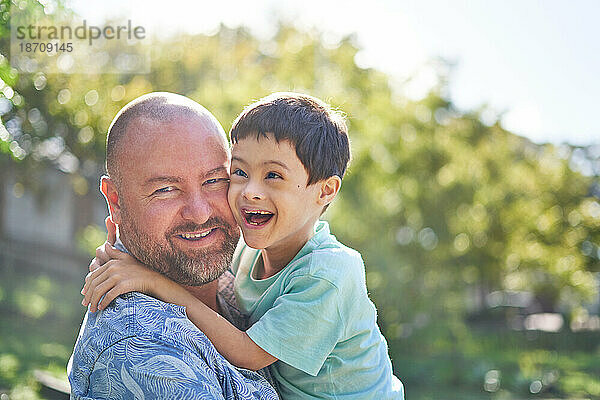 Porträt eines glücklichen Vaters  der seinen süßen Sohn mit Down-Syndrom hält