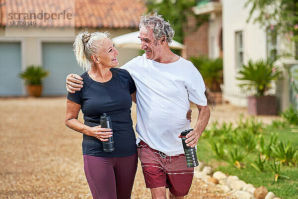 Glückliches  aktives älteres Paar  das sich umarmt und vor der Villa spazieren geht
