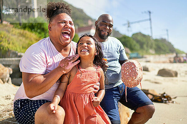 Glückliches schwules männliches Paar  das mit seiner Tochter am sonnigen Strand lacht
