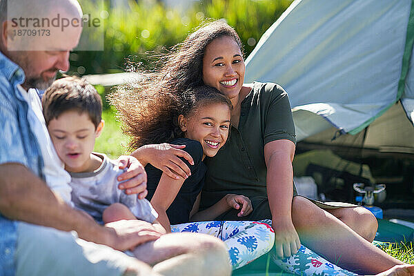 Porträt einer glücklichen Familie  die sich vor dem Zelt auf dem Sommercampingplatz umarmt