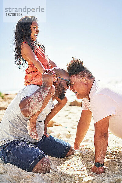 Glückliches  liebevolles schwules Männerpaar mit Tochter am sonnigen Strand