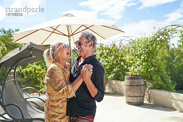 Glückliches  unbeschwertes älteres Paar  das auf der Sommerterrasse lacht und tanzt