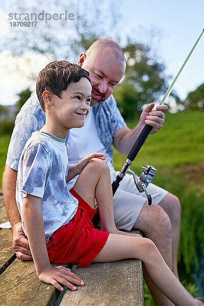 Vater und glücklicher Sohn mit Down-Syndrom angeln am Dock
