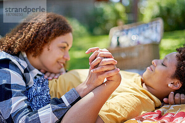 Glückliches lesbisches Paar hält Händchen und genießt Picknick im Sommerpark