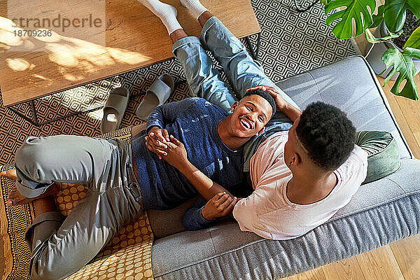 Blick von oben: glückliches junges schwules männliches Paar  das auf dem Sofa kuschelt