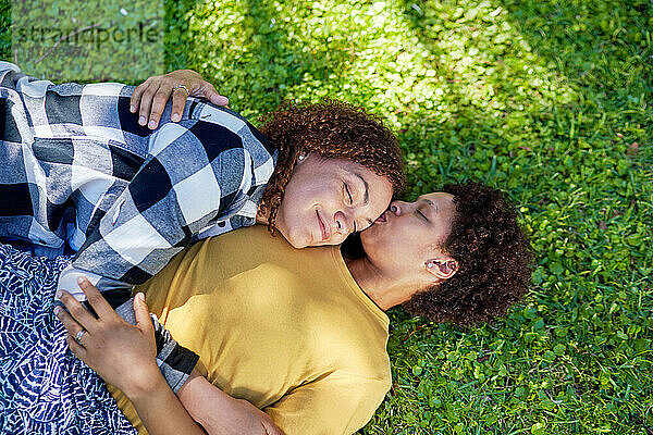 Blick von oben auf ein liebevolles  gelassenes lesbisches Paar  das im Gras liegt