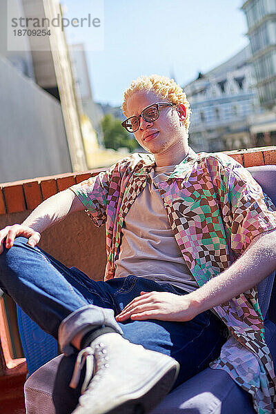Porträt eines selbstbewussten  coolen jungen Albino-Mannes auf einem sonnigen Dach