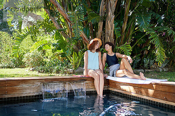 Glückliches lesbisches Paar entspannt sich im tropischen Sommerschwimmbad