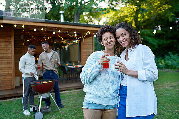 Porträt eines glücklichen lesbischen Paares beim Trinken und Grillen im Hinterhof