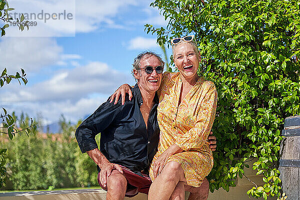 Porträt eines glücklichen  unbeschwerten älteren Paares  das auf der sonnigen Sommerterrasse lacht