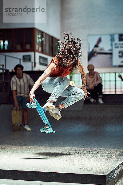 Junge Frau macht Skateboard-Stunt im Skateboardpark
