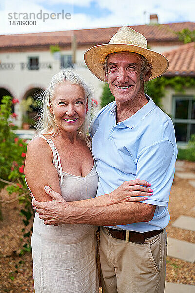 Porträt eines glücklichen älteren Paares  das sich im Garten der Villa umarmt