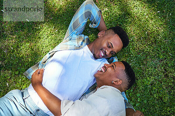 Blick von oben: glückliches  liebevolles schwules männliches Paar  das im Gras liegt