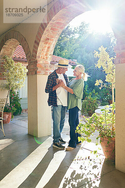 Fröhliches  liebevolles Seniorenpaar tanzt auf der sonnigen Villa-Terrasse