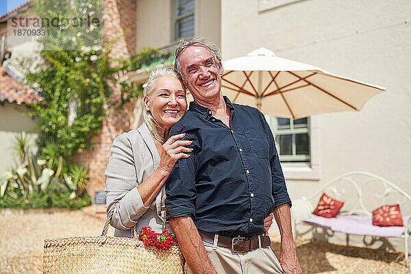 Porträt eines glücklichen älteren Paares  das sich auf der sonnigen Terrasse der Sommervilla umarmt