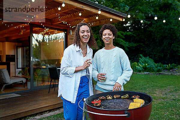 Porträt eines glücklichen lesbischen Paares beim Trinken und Grillen im Hinterhof