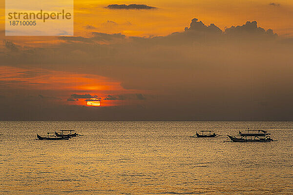 Blick auf den Sonnenuntergang und die Angelausleger am Indischen Ozean vom Strand von Kuta  Kuta  Bali  Indonesien  Südostasien  Asien