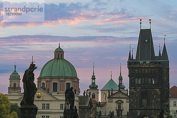 Details zu Statuen und Türmen auf der Karlsbrücke bei Sonnenaufgang  mit Kuppel der Kirche des Heiligen Franziskus von Assisi und Altstädter Brückenturm  UNESCO-Weltkulturerbe Prag  Böhmen  Tschechische Republik (Tschechien)  Europa