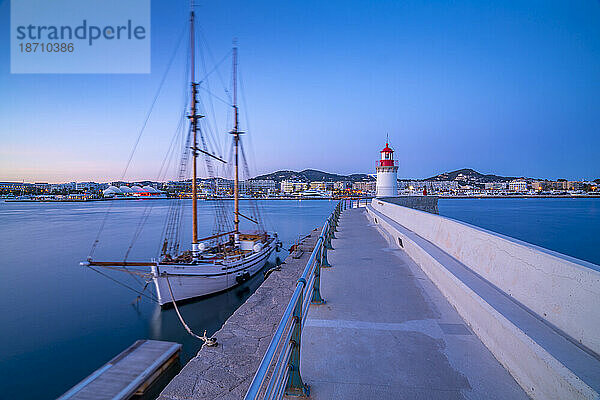 Blick auf den Hafenleuchtturm und das Segelschiff in der Abenddämmerung  UNESCO-Weltkulturerbe  Ibiza-Stadt  Eivissa  Balearen  Spanien  Mittelmeer  Europa