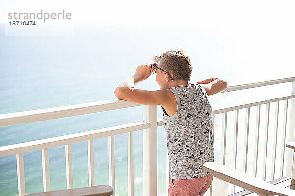 Person blickt an einem sonnigen Tag über den Balkon des Strandresorts