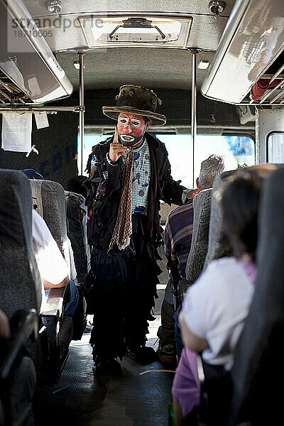 Ein evangelischer christlicher Clown predigt während einer Aufführung außerhalb von Oaxaca  Mexiko  in einem Bus das Evangelium.