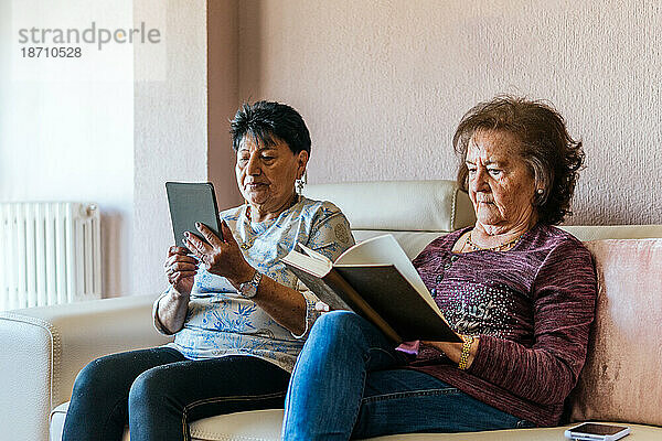 Zwei alte Frauen lesen mit elektronischem Buch und Papierbuch