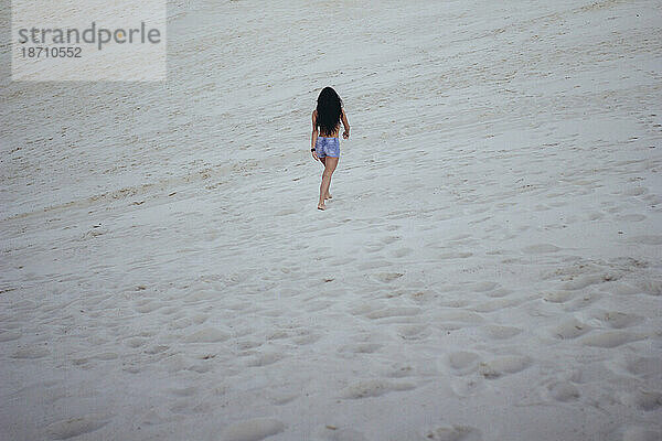 Frau geht auf dem Sand