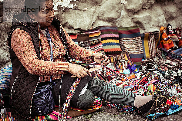 Einheimische Frau  traditionelle Weberin  sitzt und webt am Straßenrand aus Stein