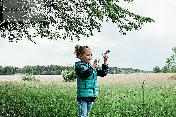 Ein junges Mädchen stand auf einem Feld und hielt eine Feder in der Hand und sah glücklich aus
