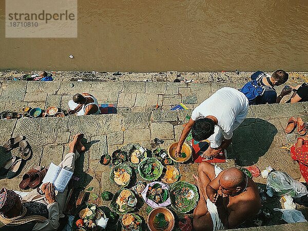 Menschen bereiten Essensopfer vor und beten am Flussufer in Asien