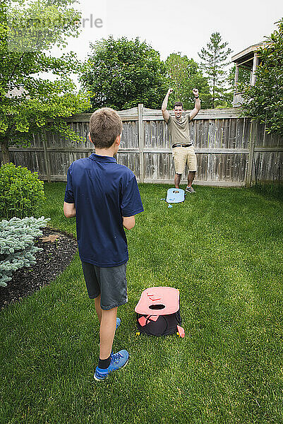 Vater und Sohn haben Spaß beim gemeinsamen Maislochspiel im Hinterhof.