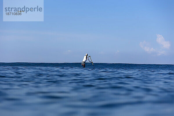 Frau paddelt im Meer