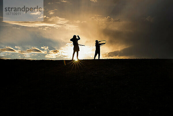 Silhouette von Geschwistern  die Hoola-Hooping machen