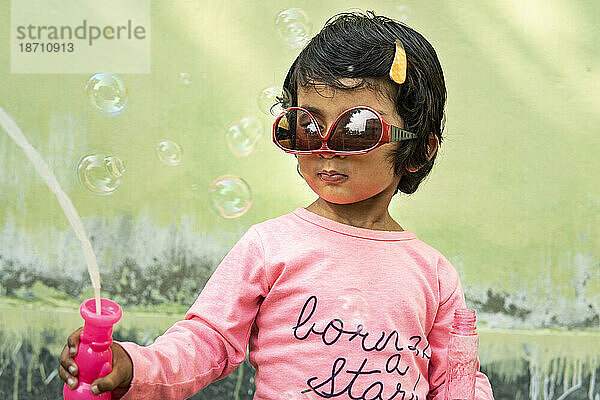 Nettes kleines Mädchen  das sich draußen mit Seifenblasen lustig macht