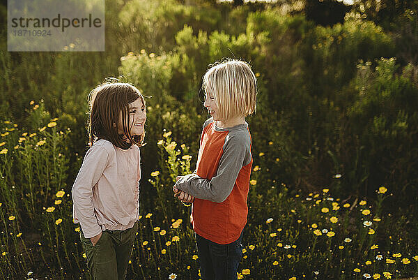 Kleiner Junge und kleines Mädchen lachen  während sie einander anschauen