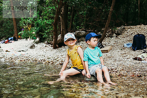 Junge Mädchen und Junge sitzen auf einem Felsen im Wasser in Barton Springs