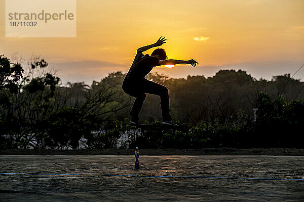 Mann springt im Sonnenuntergang auf Skateboard.Bali.Indonesien.