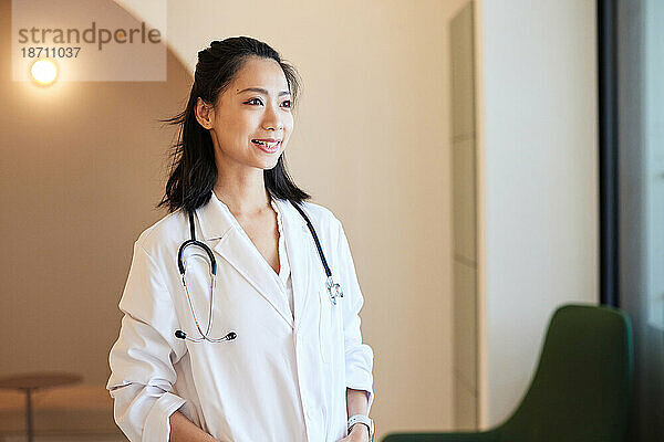 Lächelnde Ärztin mit Stethoskop steht in der Klinik