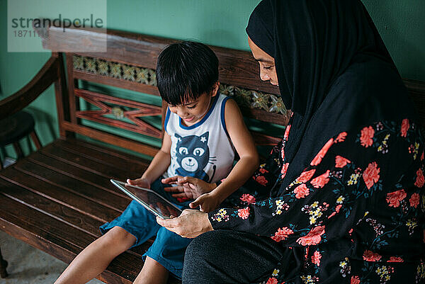 Asiatische Frau mit Sohn spielt Spiele auf einem Smart-Tablet