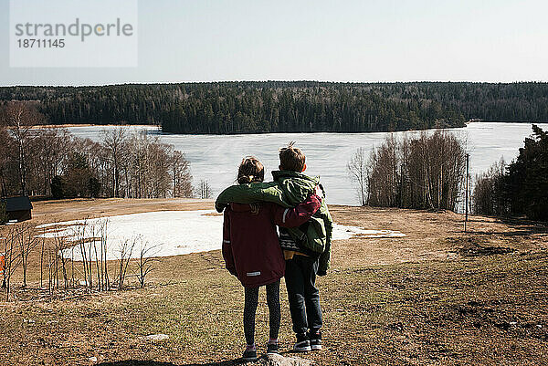 Bruder und Schwester genießen den wunderschönen Seeblick in Schweden
