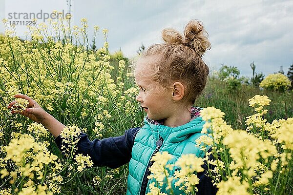 Ein junges Mädchen saß in einem Blumenfeld und sah glücklich aus