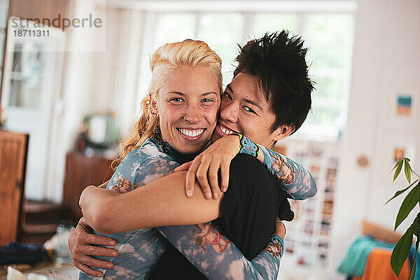 Interracial queeres Paar umarmt und lacht glücklich zu Hause